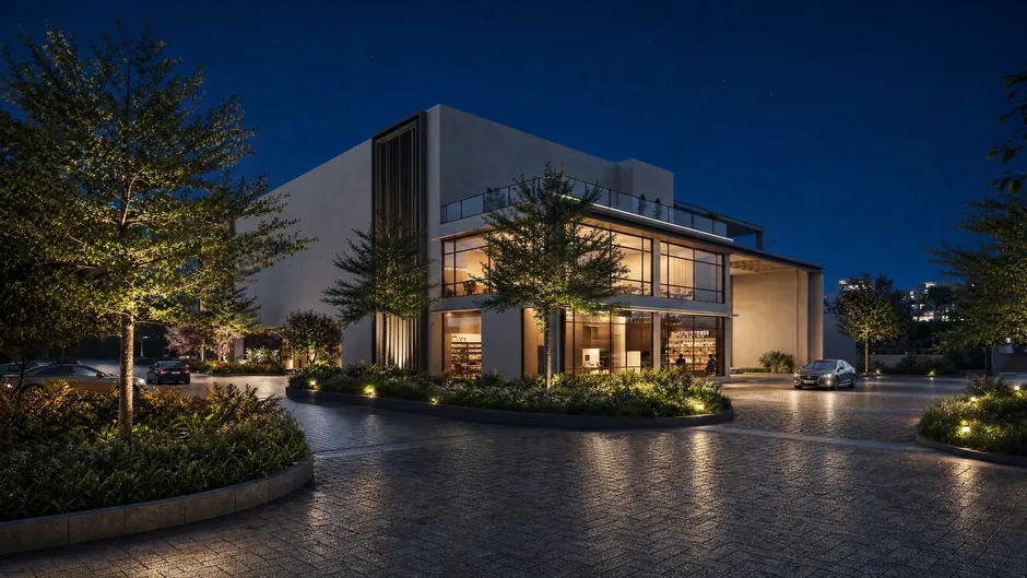 The clubhouse at Godrej Lakeside Orchard lit at night, seen across the water