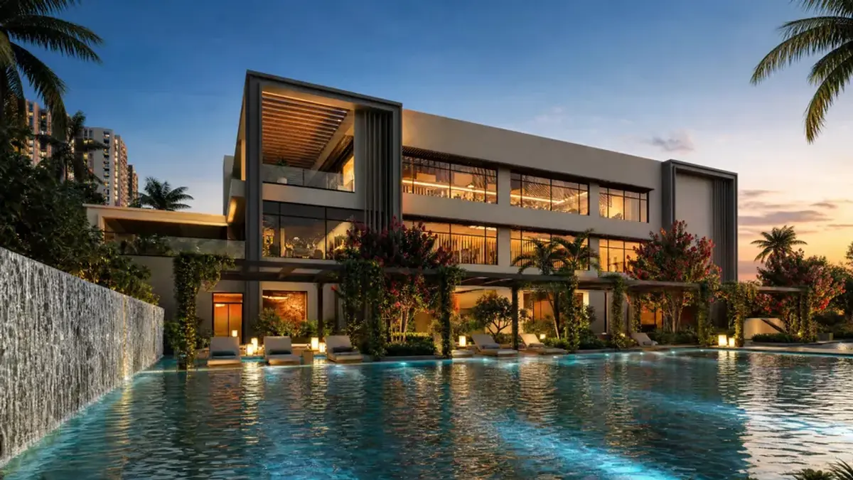 The clubhouse at Godrej Lakeside Orchard lit at dusk, seen across the pool on Sarjapur Road